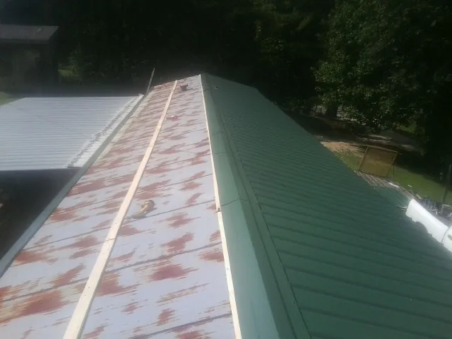 Old rusted panels beside newly installed green metal roofing — Wind Damage Roof Repair by Roofing Brothers in Fredericksburg